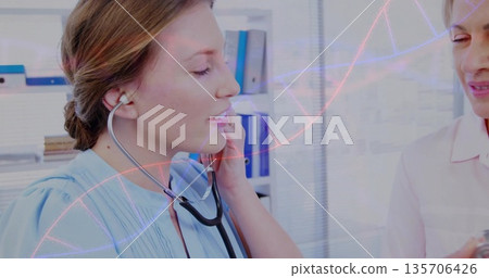 Medical professional adjusting stethoscope earpiece in clinic, with peer watching and DNA overlay 135706426