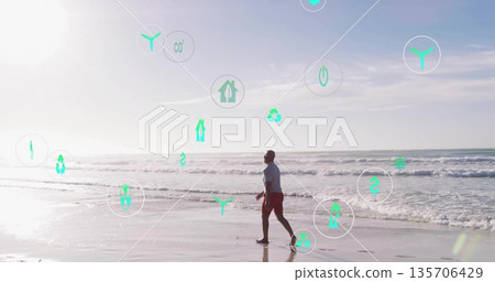 Walking male wearing t-shirt shorts along shoreline, with floating sustainability icons, copy space Walking male wearing t-shirt shorts along shoreline, with floating sustainability icons, copy space 135706429
