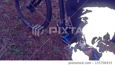 Showing lower body standing beside bicycle front wheel on forest floor, with world map overlay 135706435