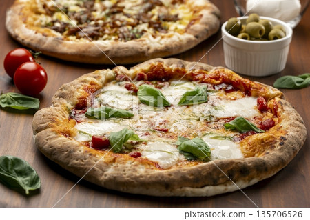Image of a Margherita pizza table topped with fresh basil Image of a Margherita pizza table topped with fresh basil 135706526