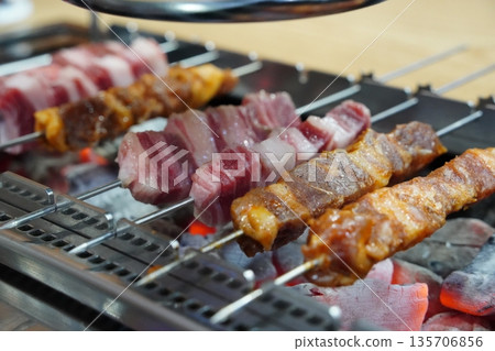 Close-Up of Assorted Lamb Skewers Grilling Over Hot Charcoal 135706856