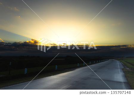 The setting sun and a straight road seen from the top of a hill in Biei, Hokkaido The setting sun and a straight road seen from the top of a hill in Biei, Hokkaido 135707148