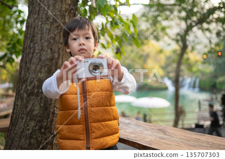 Young Boy Joyfully Capturing The Moment With A Small Camera Young Boy Joyfully Capturing The Moment With A Small Camera 135707303