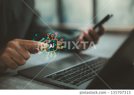 Person interacting with AI technology hologram over laptop and smartphone 135707315