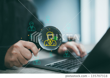 Businessman using magnifying glass to find candidate on laptop for recruitment and hiring process 135707318