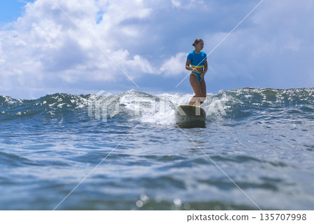 Excited Female Surf Enthusiast Raises Arms In Triumph Against Scenic Sky And Sea Excited Female Surf Enthusiast Raises Arms In Triumph Against Scenic Sky And Sea 135707998