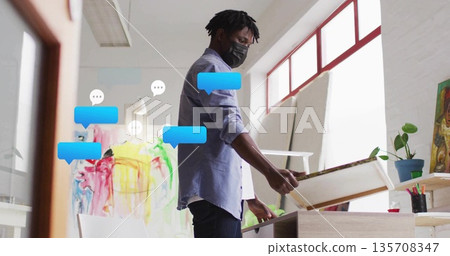 Holding blank canvas artist wearing mask working in art studio, with easel and art supplies 135708347
