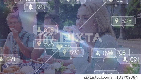 Eating woman in sweater raising pastry at park picnic table with checkered cloth, baskets, AR icons Eating woman in sweater raising pastry at park picnic table with checkered cloth, baskets, AR icons 135708364