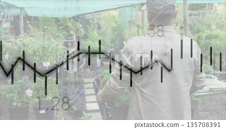 Senior man in cap, jacket pushing seedling cart through shade-cloth greenhouse, chart overlay Senior man in cap, jacket pushing seedling cart through shade-cloth greenhouse, chart overlay 135708391