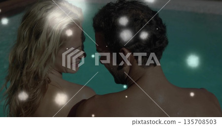 Embracing shirtless couple smiling, leaning at edge of pool water at night, with glowing light orbs Embracing shirtless couple smiling, leaning at edge of pool water at night, with glowing light orbs 135708503