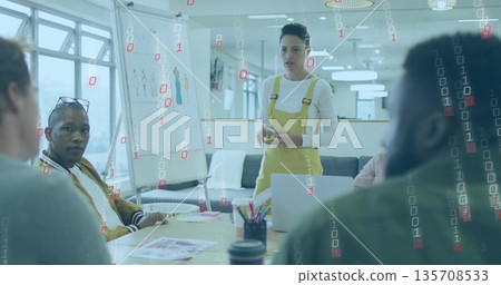 Presenting woman wearing yellow overalls in meeting room with flipchart, laptop and smartphone 135708533