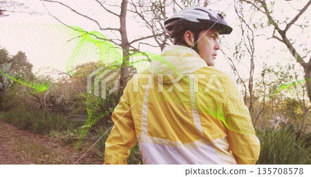 Exploring cyclist with helmet, yellow windbreaker on woodland trail, green mesh overlay, copy space Exploring cyclist with helmet, yellow windbreaker on woodland trail, green mesh overlay, copy space 135708578