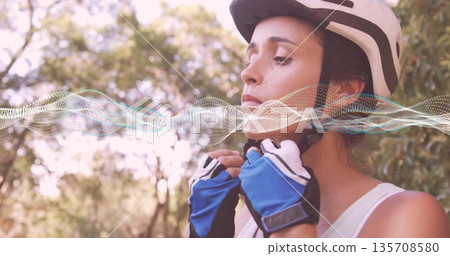 cyclist fastening helmet strap with gloves in park, waveform overlay, copy space 135708580