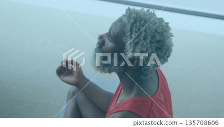 Practicing mature man meditating on blue mat in woven carpet room, red athletic top, copy space 135708606