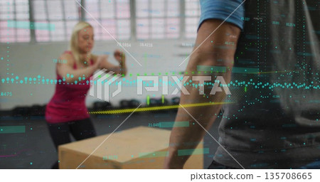 Jumping woman in sportswear onto plyometric box in gym with data overlay, weight plates, copy space 135708665