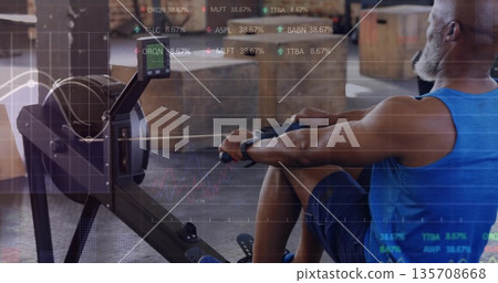 Rowing man wearing blue top, shorts on ergometer in fitness studio, with stock overlay, copy space 135708668