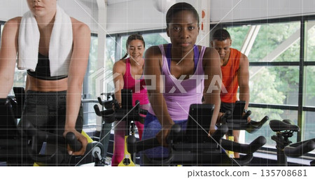 Pedaling female in purple tank top blue leggings in cycling studio, bike consoles and water bottles Pedaling female in purple tank top blue leggings in cycling studio, bike consoles and water bottles 135708681