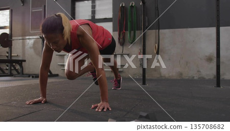 African American woman wearing sportswear performing mountain climber exercise on rubber gym floor 135708682