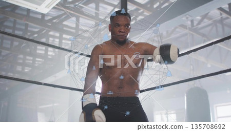 Shirtless white-gloved boxer leaning on ring ropes in gym, with punching bags and network overlay Shirtless white-gloved boxer leaning on ring ropes in gym, with punching bags and network overlay 135708692