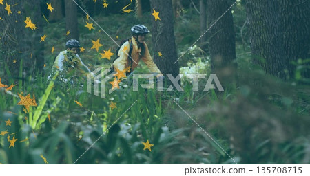 Riding cyclists wearing yellow and light jackets navigating forest trail, with star graphics Riding cyclists wearing yellow and light jackets navigating forest trail, with star graphics 135708715