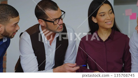 Collaborating four coworkers leaning around table in modern meeting room, with sticky note clusters Collaborating four coworkers leaning around table in modern meeting room, with sticky note clusters 135708745