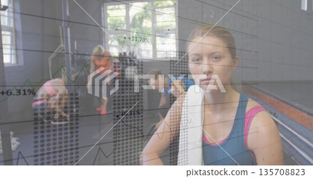Holding white towel, woman wearing blue-pink tank top in studio with chart overlay, copy space Holding white towel, woman wearing blue-pink tank top in studio with chart overlay, copy space 135708823