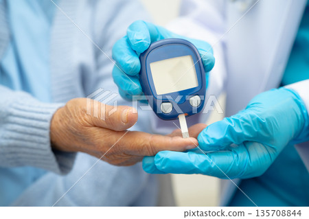 Asian doctor using digital glucose meter for check sample blood sugar level to treatment diabetes. Asian doctor using digital glucose meter for check sample blood sugar level to treatment diabetes. 135708844
