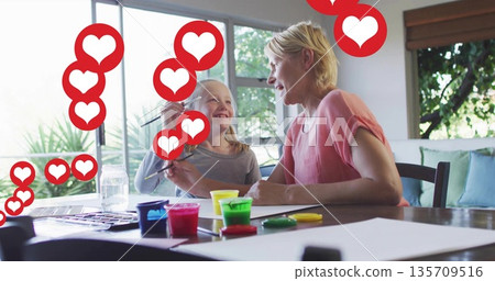 Mother and daughter painting together in home craft area, with colorful paint jars and heart icons Mother and daughter painting together in home craft area, with colorful paint jars and heart icons 135709516