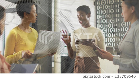 Group of four professional women collaborating in office, with laptop, tablets and metal partition 135709540