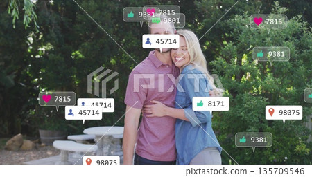 Hugging casually dressed couple sharing warm embrace on garden patio with digital speech bubbles Hugging casually dressed couple sharing warm embrace on garden patio with digital speech bubbles 135709546