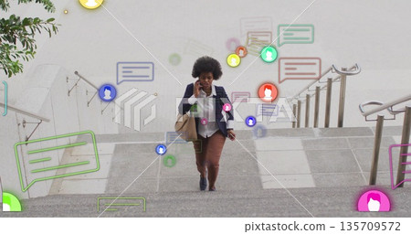 Walking executive carrying tote bag talking on smartphone climbing stone steps showing alerts 135709572