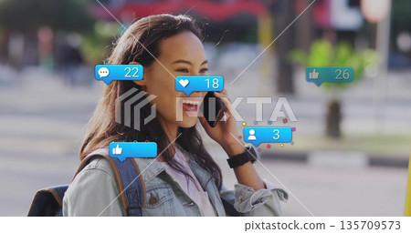 Smiling woman holding smartphone viewing social media notifications on sidewalk wearing smartwatch Smiling woman holding smartphone viewing social media notifications on sidewalk wearing smartwatch 135709573