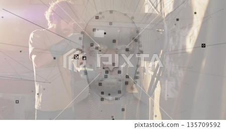 Displaying 3D mesh head in tech studio, with technician wearing tshirt and jeans adjusting scanner 135709592