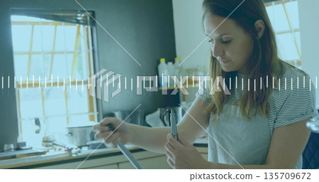 Stirring woman in gray apron, striped shirt at kitchen counter with pot and spoon, copy space Stirring woman in gray apron, striped shirt at kitchen counter with pot and spoon, copy space 135709672