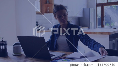 Typing woman wearing denim shirt on laptop at home kitchen, with documents, French press coffee Typing woman wearing denim shirt on laptop at home kitchen, with documents, French press coffee 135709710