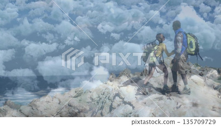 Standing couple of hikers holding hands on rocky mountaintop, with backpacks and boots, copy space Standing couple of hikers holding hands on rocky mountaintop, with backpacks and boots, copy space 135709729