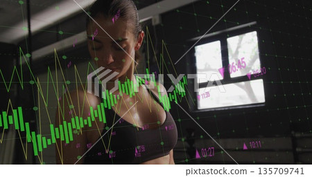 Standing woman in athletic attire analyzing candlestick overlays in gym, data-driven training Standing woman in athletic attire analyzing candlestick overlays in gym, data-driven training 135709741