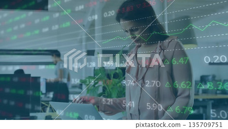 Typing businesswoman standing in open plan office with laptop, potted plant, monitors, copy space Typing businesswoman standing in open plan office with laptop, potted plant, monitors, copy space 135709751