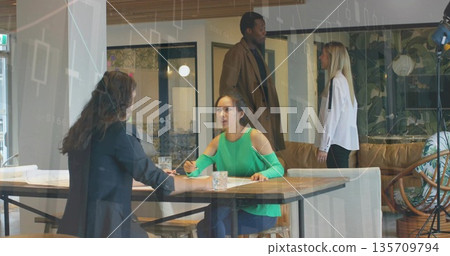 Reviewing Asian woman in green top writing at wooden table in coworking lounge, with pen, water Reviewing Asian woman in green top writing at wooden table in coworking lounge, with pen, water 135709794