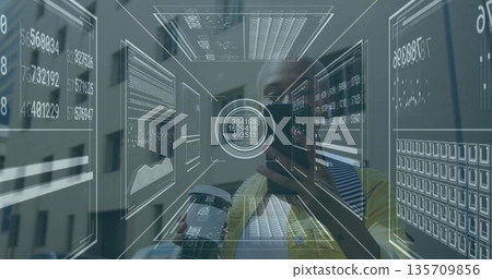 Examining tech analyst studying holographic data panels in office, holding smartphone and booklet 135709856