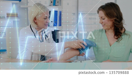 Doctor fitting blood pressure cuff on patient arm in exam room, with stethoscope, ECG, binders Doctor fitting blood pressure cuff on patient arm in exam room, with stethoscope, ECG, binders 135709888