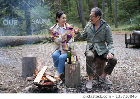 一對老年夫婦在營火前享受露營的樂趣 一對老年夫婦在營火前享受露營的樂趣 135710840