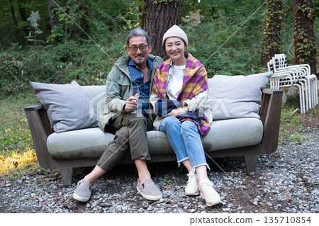 Senior couple enjoying camping in front of a bonfire 135710854