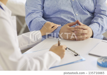 Compassionate doctor counseling overweight male patient about health and lifestyle Compassionate doctor counseling overweight male patient about health and lifestyle 135710865