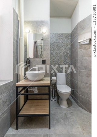Modern hostel bathroom with white vessel sink, toilet, and grey tiling Modern hostel bathroom with white vessel sink, toilet, and grey tiling 135710991