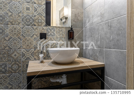 Modern bathroom interior with white vessel sink and patterned tiles 135710995