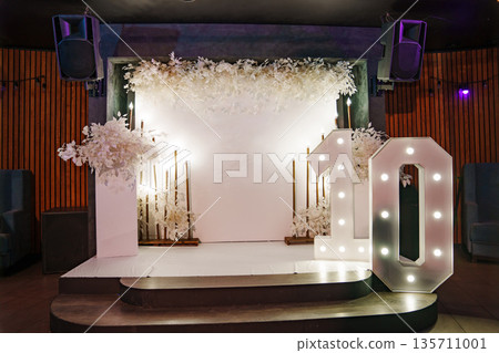 a white wall and a column with flowers, and a large number ten with light bulbs. a white wall and a column with flowers, and a large number ten with light bulbs. 135711001