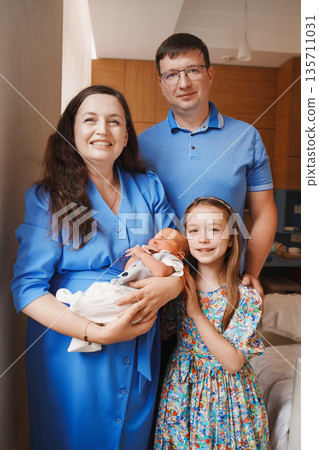 New family welcomes baby in home setting with smiles 135711031