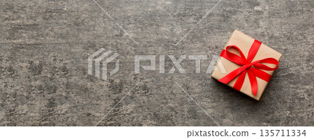 Valentine day composition: red gift box with bow and heart. Christmas present. View from above. Space for text. Holday greeting card Valentine day composition: red gift box with bow and heart. Christmas present. View from above. Space for text. Holday greeting card 135711334