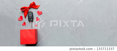 Black car key in a present box with a ribbon and red heart on colored background. Valentine day composition Top view Black car key in a present box with a ribbon and red heart on colored background. Valentine day composition Top view 135711337